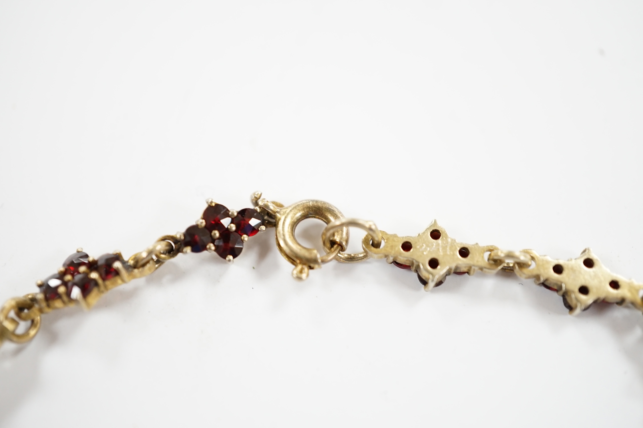 An early 20th century gilt sterling and garnet cluster set drop necklace, 45cm.